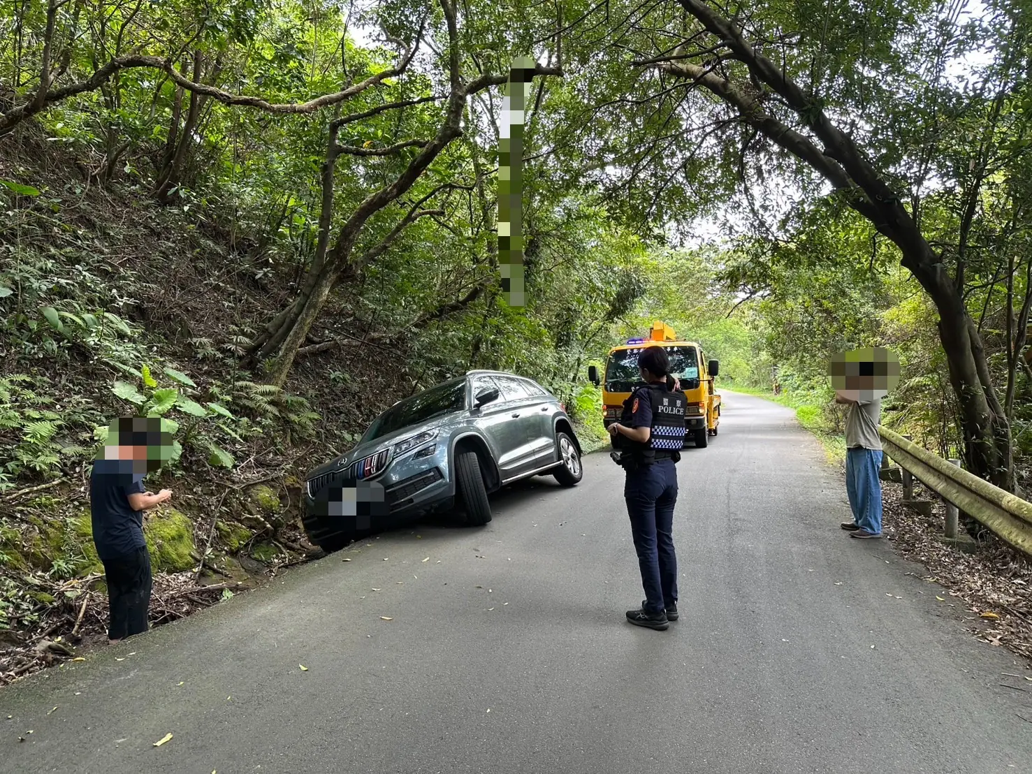 自小客車會車不慎卡山溝,警員通知拖吊業者救援。(基隆市警局提供)